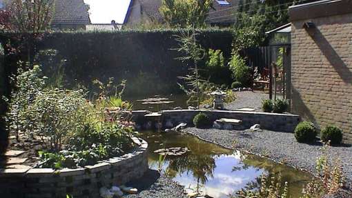 watertuin met japanse lantaren op de voorgrond een notenfagus betonsteen 20*30*6 antrasiet als grondkering en waterval