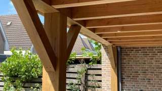 Luxe tuinoverkapping met eiken balken steekschoren sedum dak en keramische tegel vloer