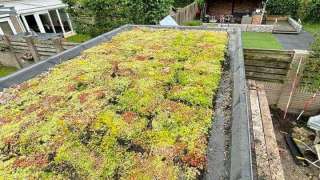 Luxe tuinoverkapping met eiken balken steekschoren sedum dak en keramische tegel vloer