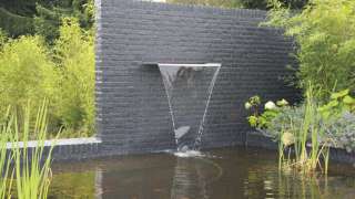 tuinmuur met rvs waterval strakke moderne tuin gebouwd met metselstenen de muur is geschilderd antrasiet