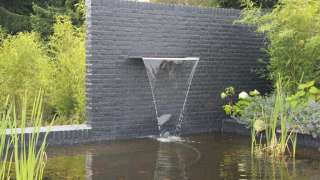 tuinmuur met rvs waterval strakke moderne tuin gebouwd met metselstenen de muur is geschilderd antrasiet