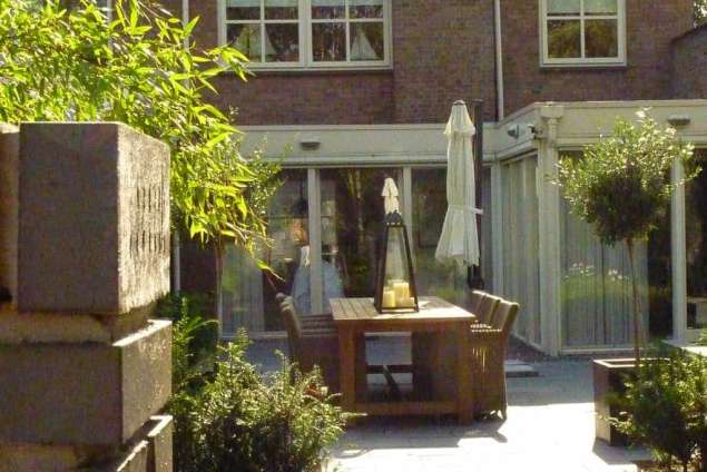 strakke tuin met op de achtergrond tafel en stoelen om op te zitten tuin in de blaak hovenier tilburg