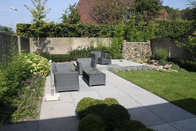 strakke tuin met gras gazon. watermuur verhoogde borders en terras. krachtige lijnen bepalen de tuin