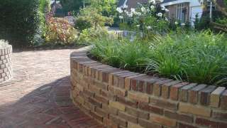 tuinmuurtjes rond hoogte 50 cm van gebakken klinkers in ronde tuin het straatwerk is gelegd in visgraadverband met lavendel en witte anemoon