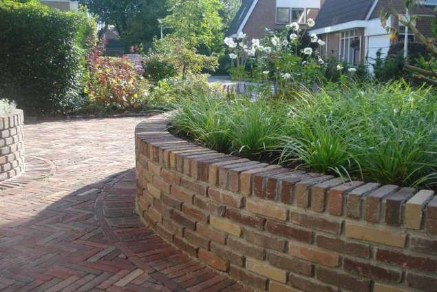 tuinmuurtjes rond hoogte 50 cm van gebakken klinkers in ronde tuin het straatwerk is gelegd in visgraadverband met lavendel en witte anemoon