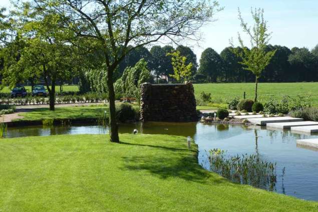 natuurlijke ogende vijver in waspik waalwijk de grasrand loopt over in de vijver. hoveniers