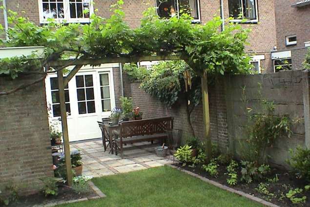 pergola met witte en blauwe druif, tegls terras 30*30 met er tussen gebakken keiformaat graszoden gelgd op vlakke ondergrond in tilburg eindhoven breda vught den bosch hovenier tuinplan beplantingplan